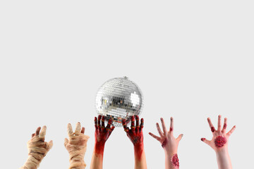 Zombie and mummy hands holding disco ball on white background. Halloween celebration