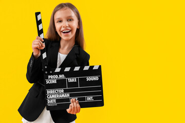 Cute little producer with movie clapper on yellow background