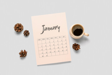 Paper calendar for January with cup of coffee and pine cones on grey background - Powered by Adobe