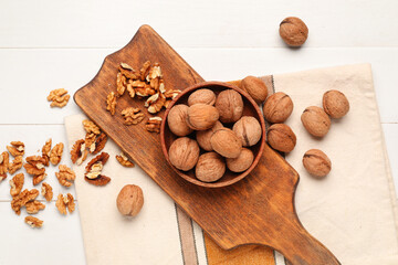 Bowl with walnuts on white wooden background
