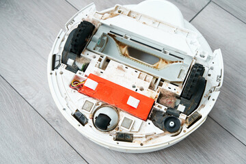 Repairing a robot vacuum cleaner that is clogged with dirt and hair. Disassembled robot vacuum cleaner. the concept of repairing home electronics.