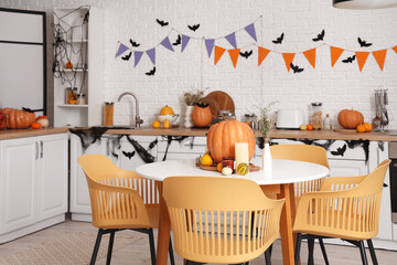 Interior of light kitchen decorated for Halloween with counters and dining table