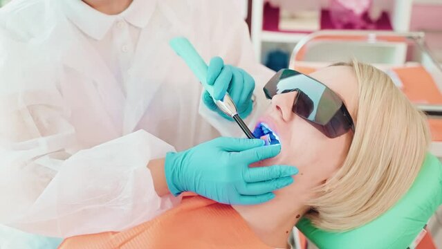 Dentist installs photopolymer seal in dentistry to patient woman.