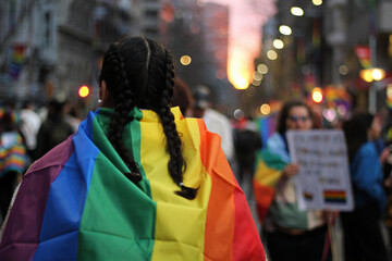 jovem leva a bandeira lgbt em marcha pela diversidade e o orgulho gay em meio aos manifestantes - obrazy, fototapety, plakaty
