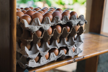 close up stack of eggs in a paper tray on a wooden cabinet
