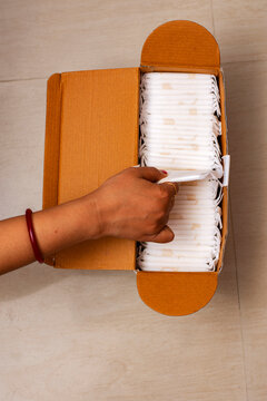 Organic ecofriendly sanitary napkin for women in box packing a female hand picking one up.