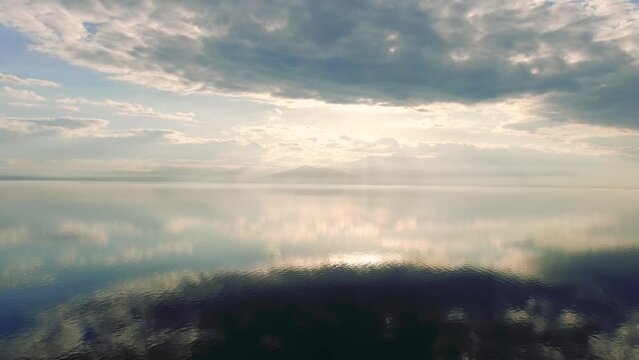 Salt lake reflecting sun and clouds, symmetry aesthetic aerial landscape panoramic movement, sunny weather, pretty cloud, shot in Salton Sea.