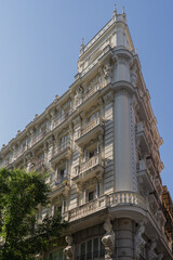 Rounded corner of classical white building with windows and balconies in Madrid, Spain