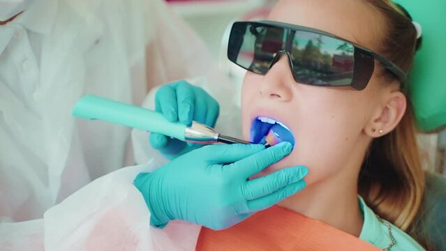 dental restoration in modern stomatological clinic for children, dentist using blue lamp