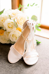 White rose bouquet next to elegant wedding shoes for a bride on her wedding day