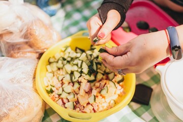 A woman is cutting vegetables for a salad on a summer picnic