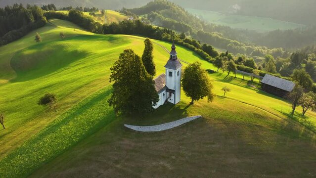 Aerial view of small beautiful church on top of a mountain in Slovenia at sunrise. Beautiful summer morning landscape. Cerkev Sveti Tomaz (St. Thomas Church)