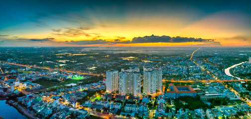 Aerial view of Saigon cityscape at evening with sunset sky in Southern Vietnam. Urban development texture, transport infrastructure and green parks