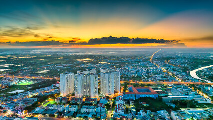 Aerial view of Saigon cityscape at evening with sunset sky in Southern Vietnam. Urban development texture, transport infrastructure and green parks