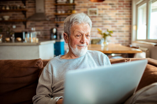 Senior man using his laptop on the couch at home