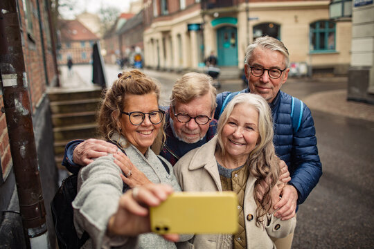 Group of senior friends taking selfies on a smartphone in the city on vacation