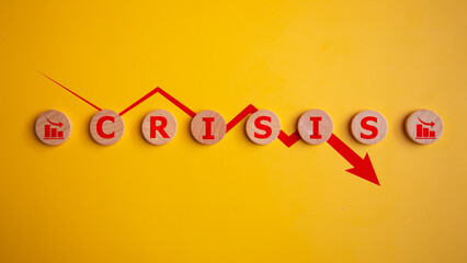 Wooden cubes with the word crisis and a red arrow down on a yellow background, business financial loss, crisis concept.