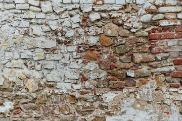 A weathered and aged stone brick wall, showing signs of decay and history, stands as a testament to time and wear