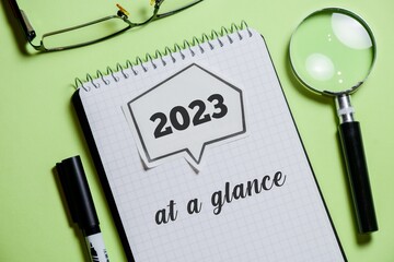 2023 At a glance text on notepad on green background. 2023 Year in review, recap, highlights concept.
