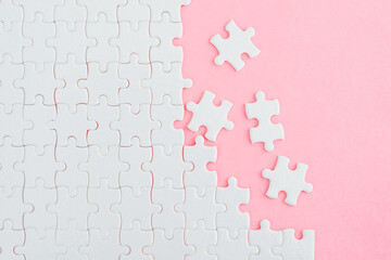 Unfinished white puzzle pieces on pink background