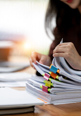 Businesswoman hands working in Stacks of paper files for searching and checking unfinished document...