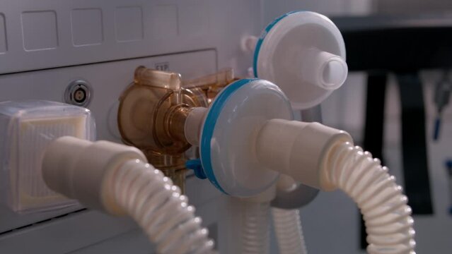 Close up tubes of life support or artificial ventilation device standing in operating room of modern hospital with advanced equipment for surgery. Bright operating block in clinic or medical facility.