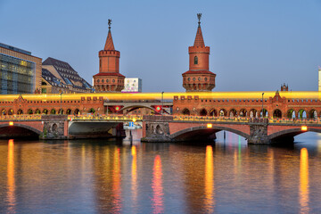 The Oberbaumbruecke in Berlin with a motion blurred yellow metro train at twilight