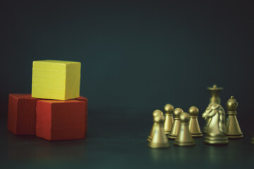 Golden chess pawn pieces on the ground with tower of wood block. Concept of leadership and success...