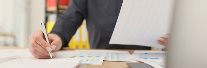 Woman writes with pen making notes while reading statistics
