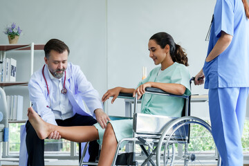Male orthopedic doctor lifting the leg of a Spanish female patient in a wheelchair. Lift your leg...
