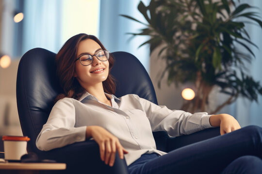Woman wearing glasses is sitting in chair. This image can be used to depict relaxation, reading, or working from home.
