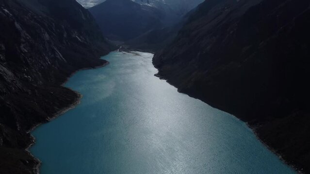 Camera panning down along blue water of Laguna Peron from Snow capped mountains to the lagoon