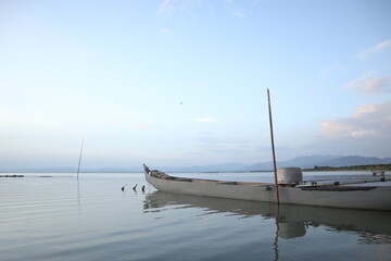 Boat in the lake at sunset. Rowing boat floating over the Limboto Lake waters. Gorontalo, Indonesia
