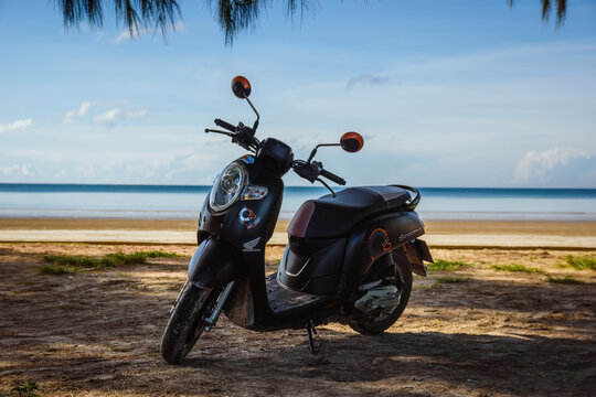 Black Honda Scoopy motorbike on a tropical beach in Ko Lanta, Krabi, Thailand.