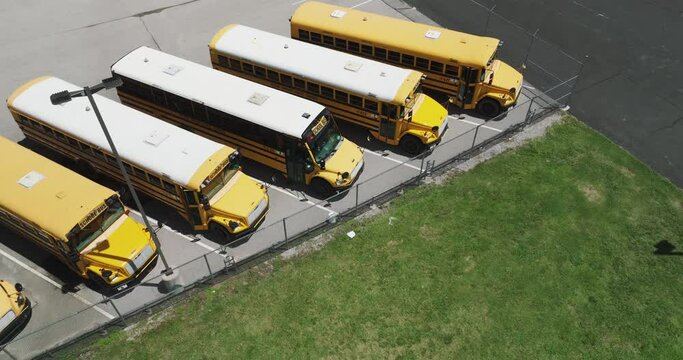 Row Of School Bus Used To Transport Students Parked In The Parking Lot. - aerial