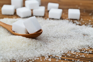Spoon with sugar cubes on top of granulated sugar - obrazy, fototapety, plakaty