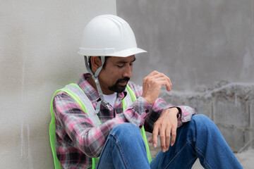 Hopeless builder worker sitting in construction site meet financial crisis, stressed Asian...