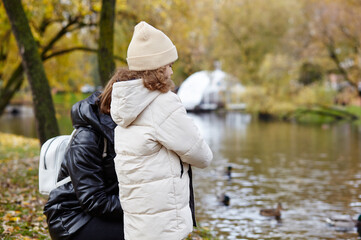 Hello october. Mother and daughter are walking in the autumn city park. Parent and little child having fun outdoors