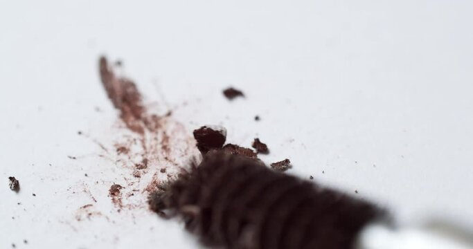 Smudging a bit of crumbly dark-brown mascara, using a ball-tipped bristle applicator on an empty whiteboard palette.