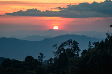 Fototapeta na wymiar sunset behind beautiful mountain range with dramatic cloud and orange sky (Tak province, Thailand)