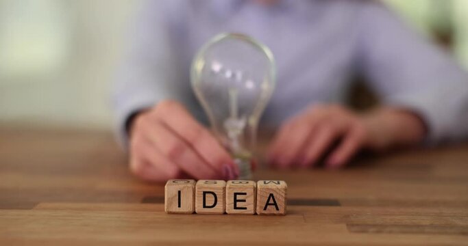 Business woman holding light bulb and word idea. Development and promotion of creative ideas in business