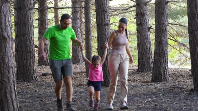 Joyful Family Run in the Woods - A lively trio in summer sportswear runs hand-in-hand, delighting in their shared forest adventure.