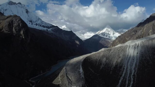 Camera rising up to reveal pale blue water of Laguna Paron between snowcapped mountain peaks