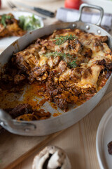 Casserole with lasagna noodles, braised and shredded meat, mushrooms and cheese in a roasting pan