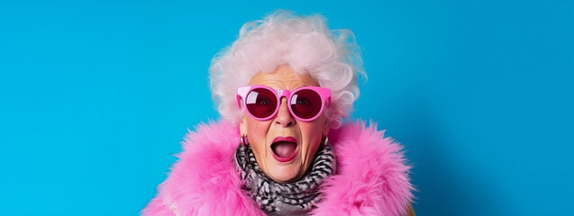 Colorful studio portrait of eccentric elderly granny wearing pink fur and sunglasses, blue background, shocked and judgmental expression - obrazy, fototapety, plakaty