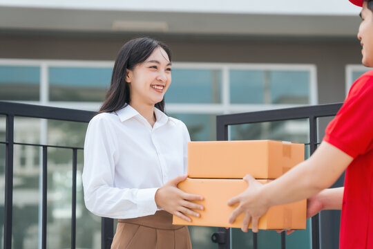 Asian people received product box from male delivery service person, modern e-commerce, home deliveries, convenient shopping experience, trustworthy doorstep service captured in moment.