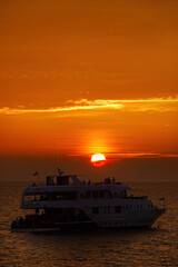 Beautiful wide twilight sunset evening sky reflect on sea water with silhouette boat in ocean and epic cloud pattern background landscape with love, peace and loneliness mood vibes on vacation trip.