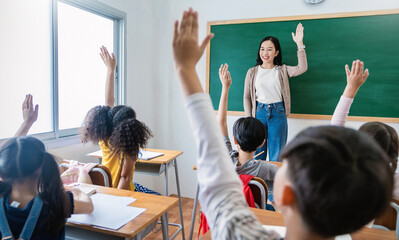 Multicultural group of students raising hands in class on lecture education, elementary school, learning people concept. Group team work of school kids with teacher sit in classroom and raising hands