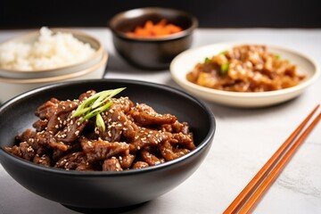 bulgogi beef strips next to a bowl of soy sauce and sesame seeds