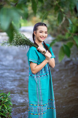 Portrait of cheerful pretty woman in green dress holding bunch of flowers, while walking outdoor riverside in summer. Girl walking outdoors with bouquet. Karen dress. Summer, leisure, holiday concept